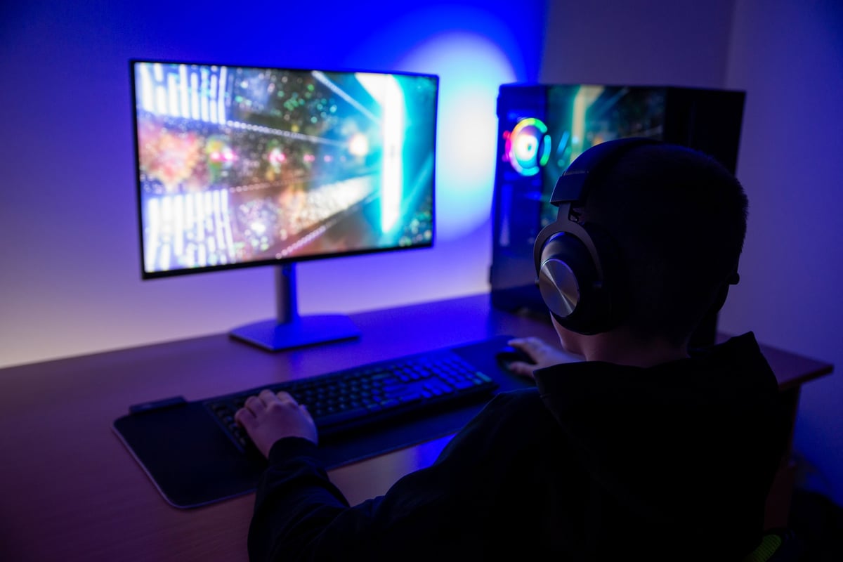 Gamer using a desktop PC with RGB lighting in a dark room